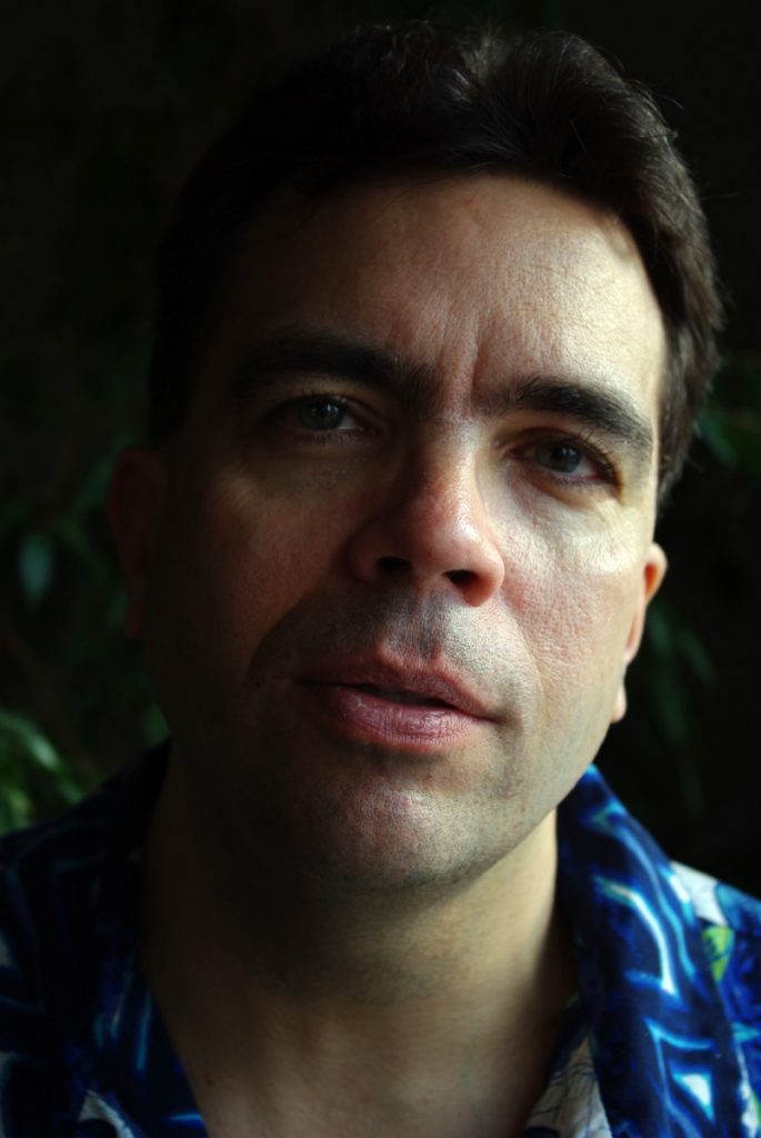 Head shot of long-time NER essayist Ben Miller, half in shadow with his flannel shirt