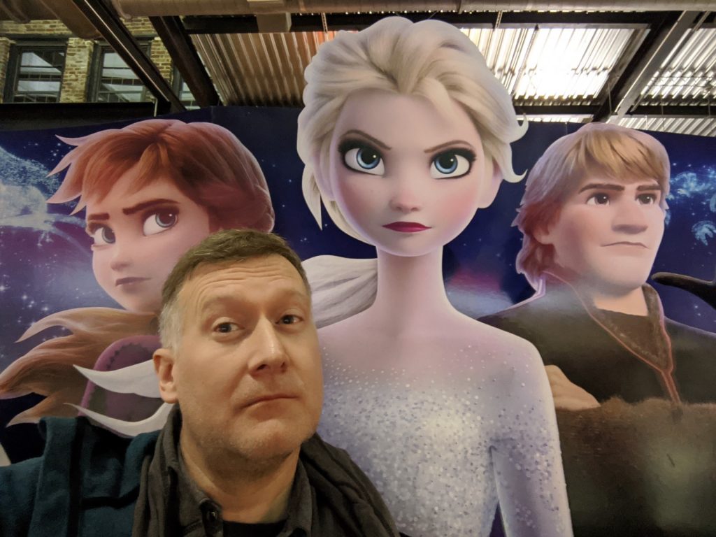 J. M. Tyree in front of a poster of Frozen.